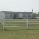 tan/blue home with white fence and green grass