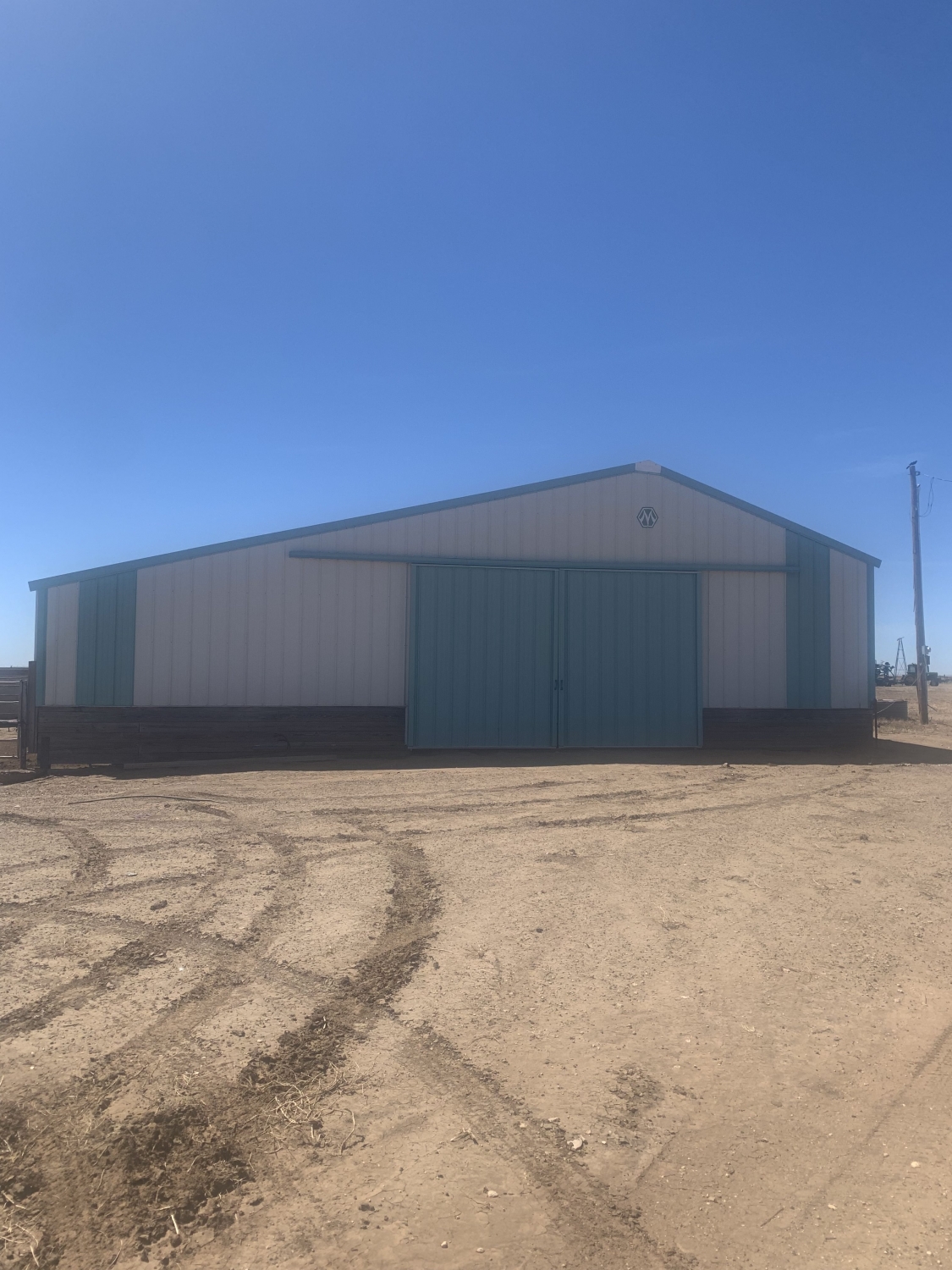 white metal barn with baby blue doors in a dirt field